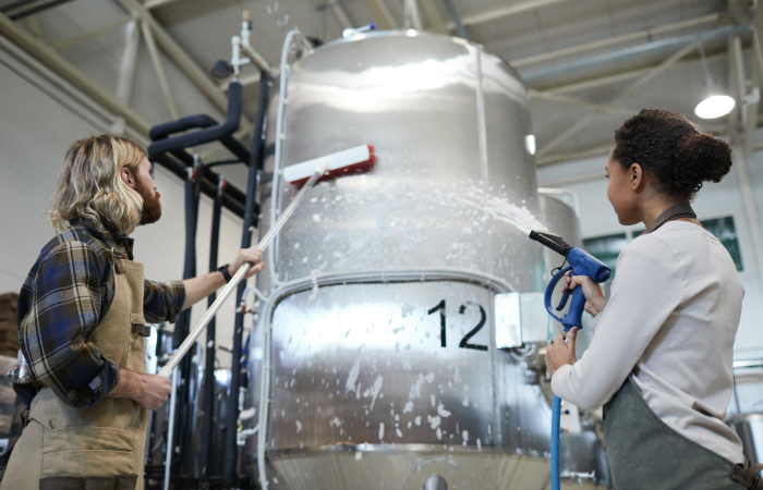 two-workers-cleaning-machines-at-factory-2023-11-27-05-33-16-utc